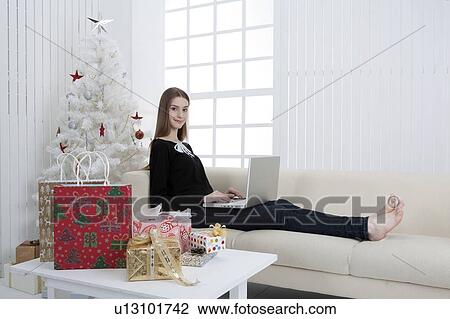 Young woman sitting on sofa and using laptop View Large Photo Image Stock Image - Young woman sitting on sofa and using laptop. Fotosearch