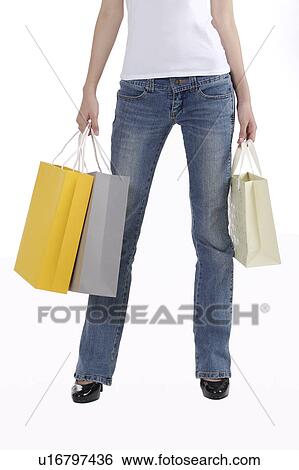 Young woman standing and holding shopping bags View Large Photo Image Stock Photograph - Young woman standing and holding shopping bags. Fotosearch