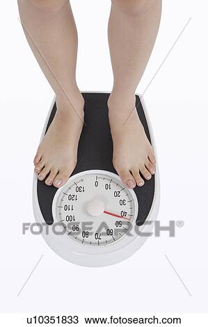 Young woman standing on weight scale View Large Photo Image Stock Image - Young woman standing on weight scale. Fotosearch
