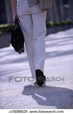 Stock Photography - Young woman walking and holding a briefcase. Fotosearch