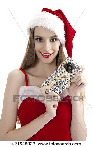 Young woman wearing Santa hat and holding a wrapped gift with smile View Large Photo Image Stock Image - Young woman wearing Santa hat and holding a wrapped gift with smile. Fotosearch