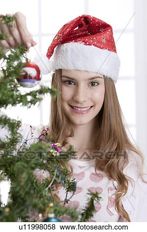 Young woman wearing Santa hat and holding a Christmas bauble View Large Photo Image Stock Photo - Young woman wearing Santa hat and holding a Christmas bauble. Fotosearch