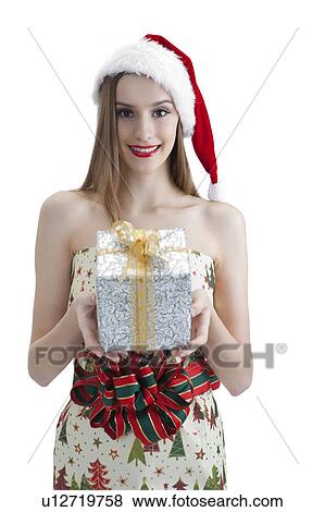 Stock Photo - Young woman wearing Santa hat and holding a wrapped gift with smile. Fotosearch