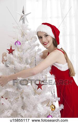 Young woman wearing Santa hat and holding a white Christmas tree with smile View Large Photo Image Stock Photo - Young woman wearing Santa hat and holding a white Christmas tree with smile. Fotosearch