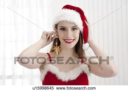 Young woman wearing Santa hat and holding earring of star shape View Large Photo Image Stock Photography - Young woman wearing Santa hat and holding earring of star shape. Fotosearch