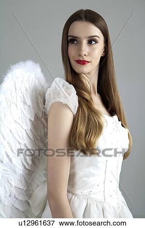 Young woman wearing white dress with wings and looking away View Large Photo Image Stock Photo - Young woman wearing white dress with wings and looking away. Fotosearch