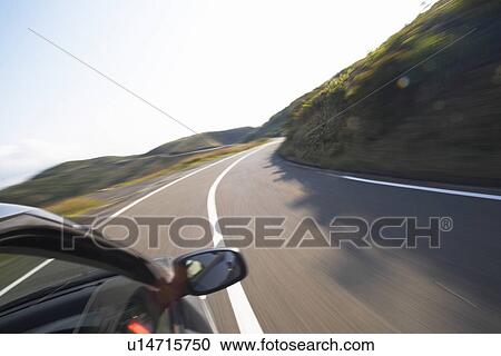 Stock Image - A Car Running on Winding Road in Mountain. Fotosearch