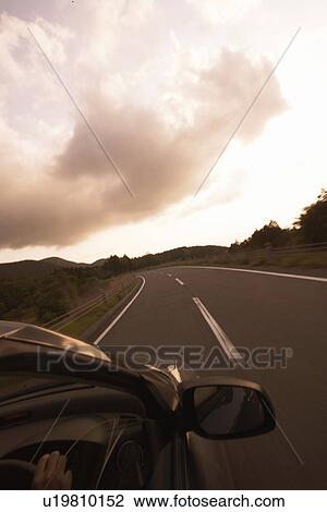 Stock Image - A Car Running on Winding Road in Mountain. Fotosearch