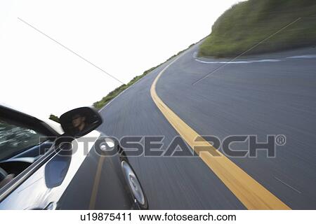 Stock Image - A Car Running on Winding Road in Mountain. Fotosearch