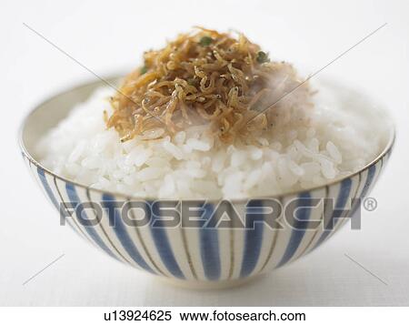 Stock Photography - Bowl of rice with whitebaits, close up, white background. Fotosearch