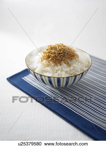 Stock Image - Bowl of rice with whitebaits, white background. Fotosearch
