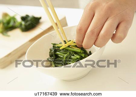 Stock Photo - Bowl of spinach and yuzu fruit, close up. Fotosearch