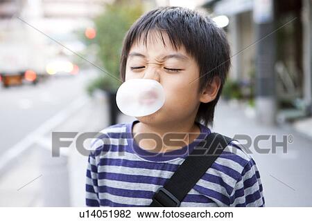 Stock Image - Boy blowing up a bubble gum. Fotosearch