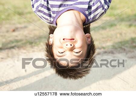 Stock Photo - Boy hanging from monkey bars. Fotosearch