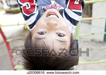 Stock Photograph - Boy hanging from monkey bars. Fotosearch