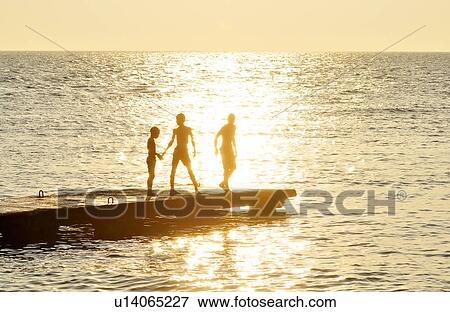 Stock Photo - Boy playing at pier at dusk. Fotosearch