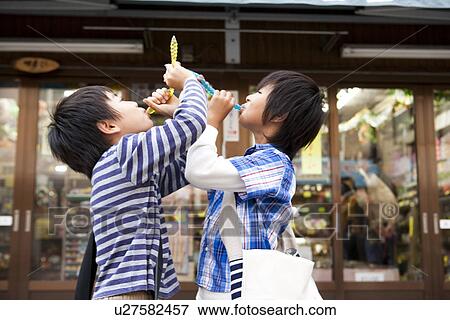 Stock Photo - Boys drinking juice in front of Dagashi-ya. Fotosearch