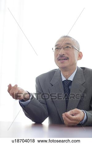 Businessman sitting at desk, smiling View Large Photo Image Stock Photo - Businessman sitting at desk, smiling. Fotosearch