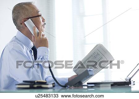 Stock Image - Businessman using phone in office. Fotosearch