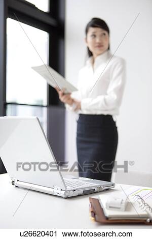 Stock Image - Businesswoman standing with newspaper in her hand . Fotosearch