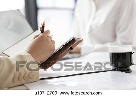 Stock Photo - Businesswoman writing in her diary. Fotosearch