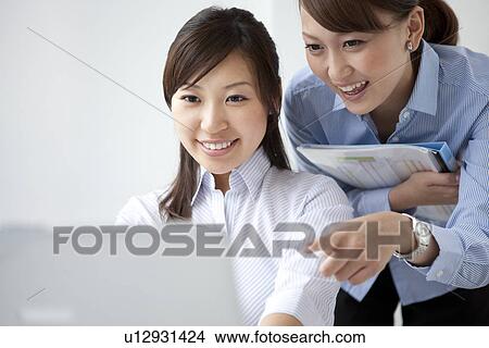 Picture - Businesswomen looking at laptop . Fotosearch