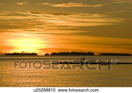 Couple standing by the sea at dusk View Large Photo Image Stock Image - Couple standing by the sea at dusk. Fotosearch