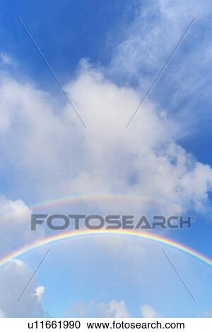 Stock Image - Double Rainbow in the Blue Sky. Fotosearch