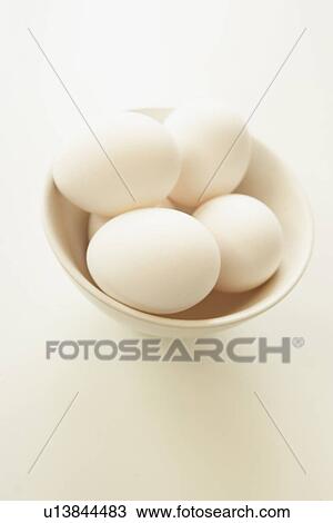 Stock Image - Eggs in bowl, close up, white background. Fotosearch