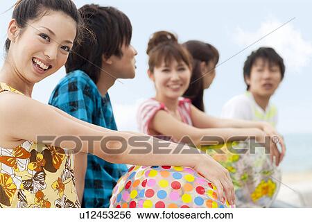 Five young people sitting on beach, woman looking at camera View Large Photo Image Stock Photograph - Five young people sitting on beach, woman looking at camera. Fotosearch
