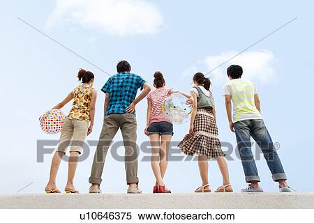 Five young people standing on breakwater, women holding beach balls View Large Photo Image Stock Photography - Five young people standing on breakwater, women holding beach balls. Fotosearch