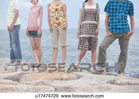 Five young people standing side by side at beach View Large Photo Image Stock Photo - Five young people standing side by side at beach. Fotosearch
