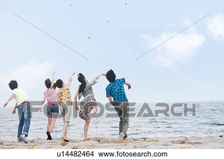 Picture - Five young people throwing stones over sea. Fotosearch