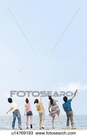Stock Image - Five young people throwing stones over sea. Fotosearch