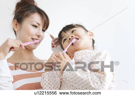 Stock Photograph - Girl and woman brushing teeth, white background. Fotosearch