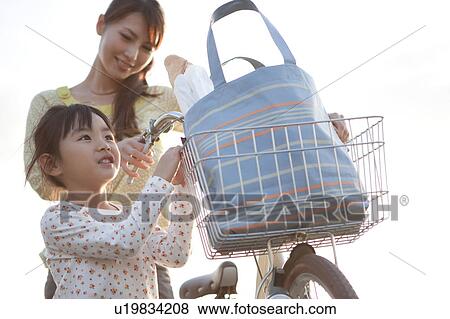Girl and woman pushing bicycle, white background View Large Photo Image Stock Photo - Girl and woman pushing bicycle, white background. Fotosearch