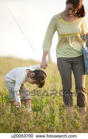 Girl and woman walking at riverbank hand in hand, girl picking flowers View Large Photo Image Stock Image - Girl and woman walking at riverbank hand in hand, girl picking flowers. Fotosearch