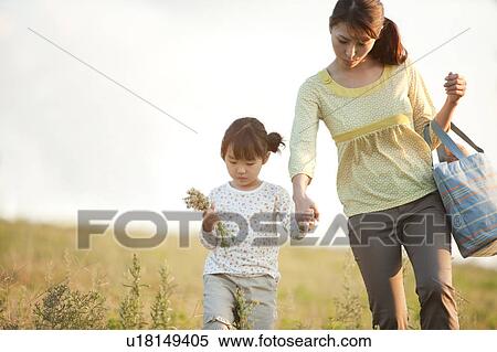 Stock Photography - Girl and woman walking in field hand in hand. Fotosearch