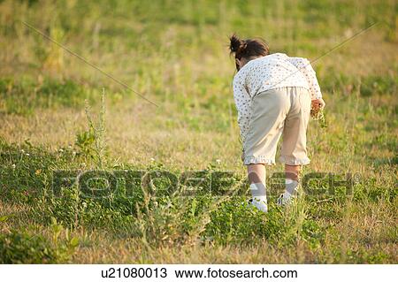 Stock Image - Girl bending over at riverbank. Fotosearch