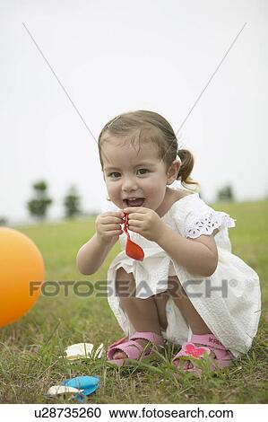 Stock Image - Girl blowing up a balloon. Fotosearch