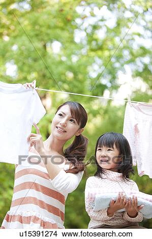 Girl helping mother drying laundry, smiling View Large Photo Image Picture - Girl helping mother drying laundry, smiling. Fotosearch