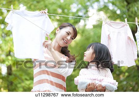 Girl helping mother drying laundry, smiling View Large Photo Image Stock Photo - Girl helping mother drying laundry, smiling. Fotosearch