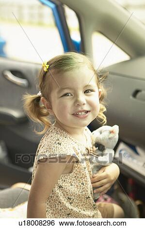 Stock Photograph - Girl holding a teddy bear in a car. Fotosearch