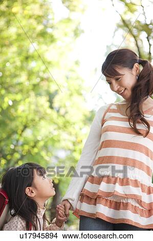 Picture - Girl holding mother's hand, looking up. Fotosearch