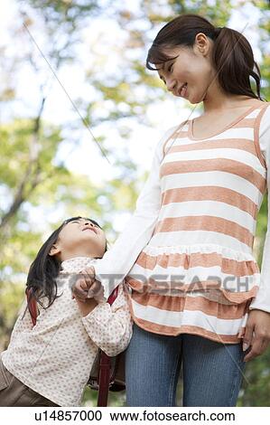Stock Image - Girl holding mother's hand, looking up. Fotosearch