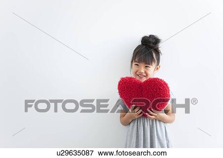 Girl holding red heart cushion, white background View Large Photo Image Stock Photo - Girl holding red heart cushion, white background. Fotosearch