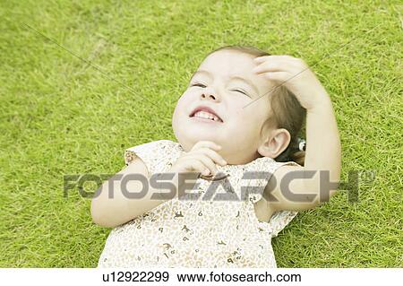 Stock Photo - Girl lying down on grass. Fotosearch