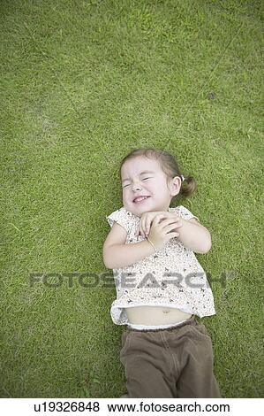 Girl lying down on grass View Large Photo Image Stock Photo - Girl lying down on grass. Fotosearch