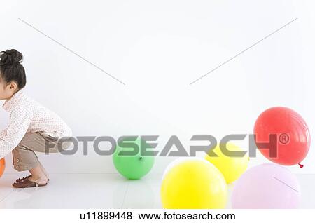 Stock Photo - Girl playing with balloons, white background. Fotosearch