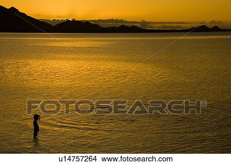 Picture - Girl standing in water at dusk. Fotosearch